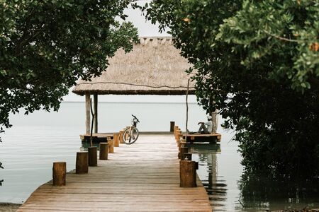 A man sitting on a pier next to his bicycle watching the seaの写真素材