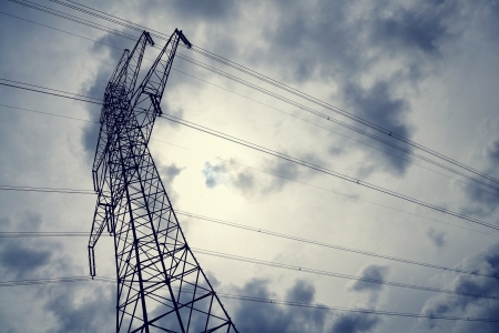 Electricity pylon against sun behind cloudsの写真素材