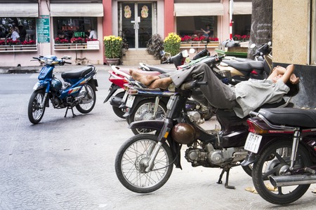 HO CHI MINH CITY - FEBRUARY 4: Man rests on scooter on  street on February 4, 2012 in Ho Chi Minh City, Vietnam.のeditorial素材
