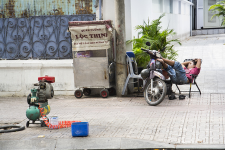 HO CHI MINH CITY - FEBRUARY 4: Man rests on scooter on  street on February 4, 2012 in Ho Chi Minh City, Vietnam.のeditorial素材