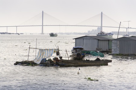 Ratty boats and raft houses with fish cages floating on Mekong river on a cloudy day in My To, Vietnamの写真素材