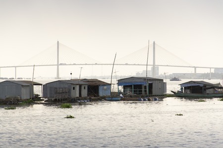 Ratty boats and raft houses with fish cages floating on Mekong river on a cloudy day in My To, Vietnamの写真素材