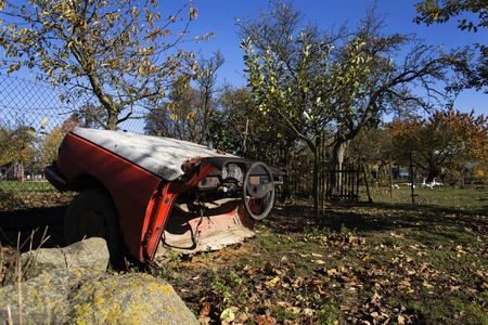 Rusty vintage car cut in half on a sunny day in autumn gardenの写真素材