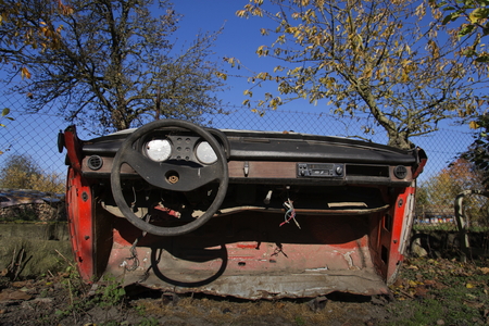 Rusty vintage car cut in half on a sunny day in autumn gardenの写真素材