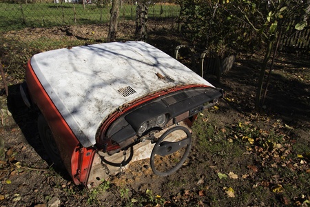 Rusty vintage car cut in half on a sunny day in autumn gardenの写真素材