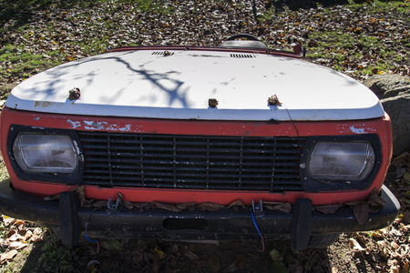 Rusty vintage car cut in half on a sunny day in autumn gardenの写真素材