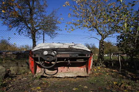 Rusty vintage car cut in half on a sunny day in autumn gardenの写真素材