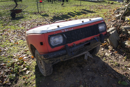 Rusty vintage car cut in half on a sunny day in autumn gardenの写真素材
