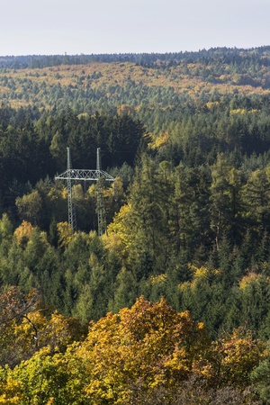 Electricity pylon in colorful forest in autumn natureの写真素材