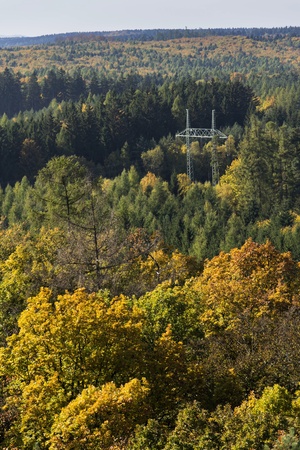 Electricity pylon in colorful forest in autumn natureの写真素材