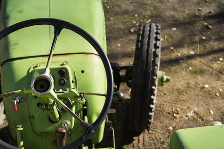 Old green vintage tractor stands on farm yard on a sunny autumn dayの写真素材