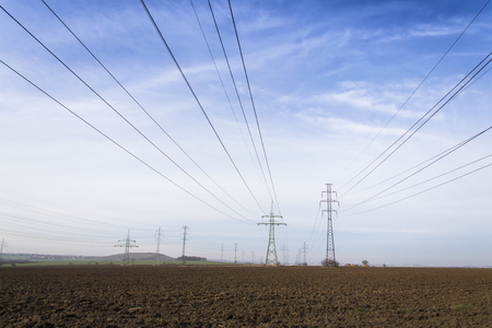 Electricity pylons leading from distribution power station blue cloudy sky backgroundの写真素材