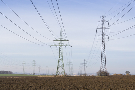 Electricity pylons leading from distribution power station blue cloudy sky backgroundの写真素材