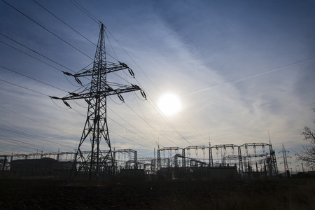 Electricity pylon from distribution power station with sun in backgroundの写真素材