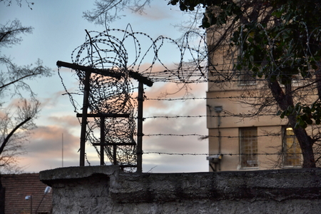 Barbed wire fence layed around prison wallsの写真素材