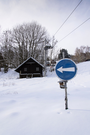 Blue direction traffic sign on end of ski lift in snowy mountainsの写真素材