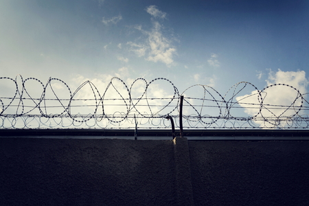 Filtered vintage picture of barbed wire prison fence detailの写真素材
