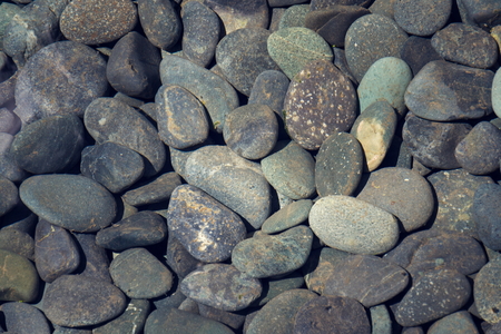 Grey stone pebbles under water lake bed backgroundの写真素材