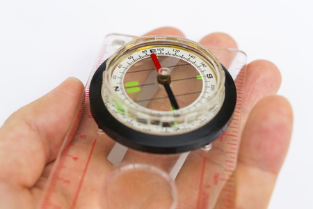 Detail of hand holding glass compass on white backgroundの写真素材