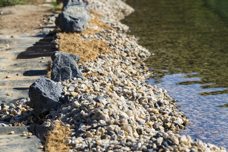 Rocks on bank of natural swimming pond or pool NSPの写真素材