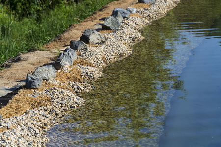 Rocks on bank of natural swimming pond or pool NSPの写真素材