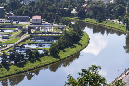 Aerial view of river meandering around sewage water treatment plantの写真素材