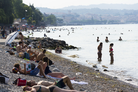 DESENZANO DEL GARDA, ITALY - JULY 30: People sunbathing on beach on 30 July 2016 in Desenzano del Garda, Italy.のeditorial素材