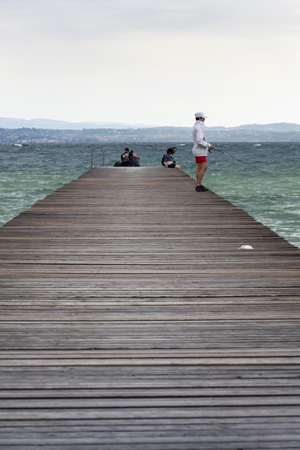 SIRMIONE, ITALY - JULY 31: People on wooden pier on Lago di Garda on 31 July 2016 in Sirmione, Italy.のeditorial素材