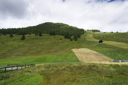 Man rakes hay with truck on steep hillside, Livigno, Italyの写真素材