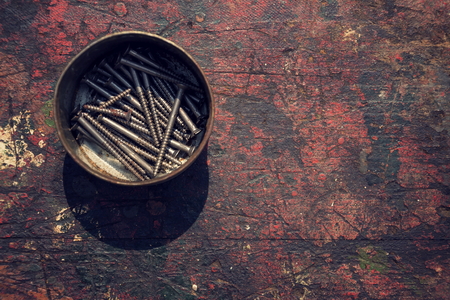 Filtered screws and bolts in tin can on wooden backgroundの写真素材