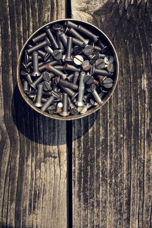Filtered screws and bolts in tin can on wooden backgroundの写真素材