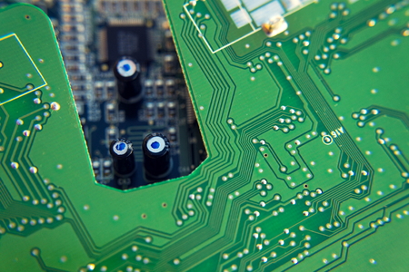 Filtered green computer motherboard circuit above blue motherboard holeの写真素材