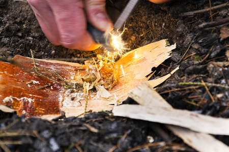 Male hand starts fire with magnesium fire steel, fire strikerの写真素材
