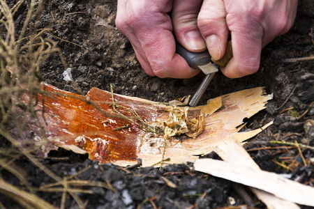 Male hand starts fire with magnesium fire steel, fire striker