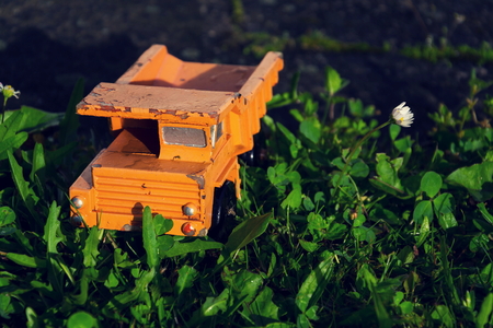 Filtered vintage orange car toy truck on green grassの写真素材