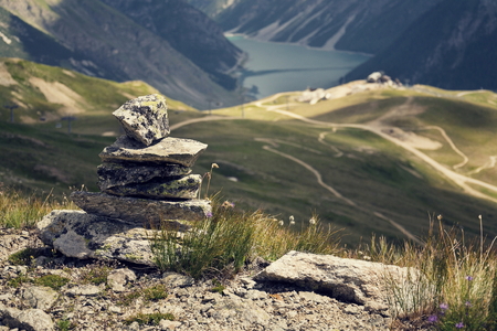 Filtered balanced stone pyramid in with blue water mountain lake