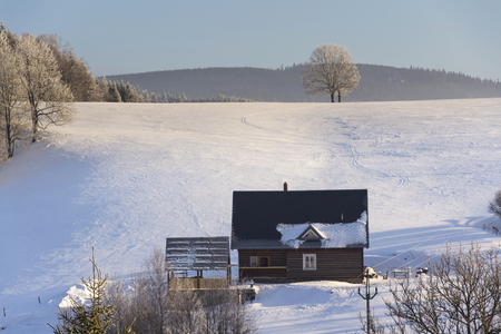 Timbered cottage in frosty mountains country in sunny winter dayの写真素材