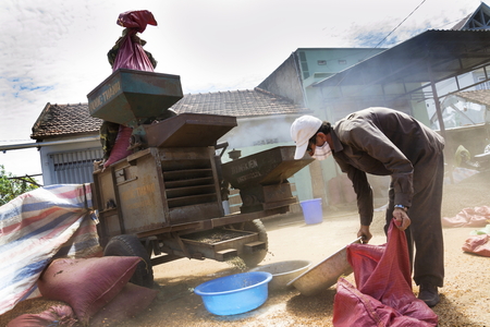 NAM BAN, VIETNAM - FEBRUARY 11: Men working on coffee beans sorting machine on street on February 11, 2012 in Nam Ban, Vietnam.のeditorial素材