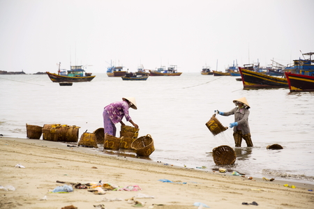 MUI NE, VIETNAM - FEBRUARY 7: Woman washing baskets for anchovies used for fish sauce on February 7, 2012 in Mui Ne, Vietnam.のeditorial素材