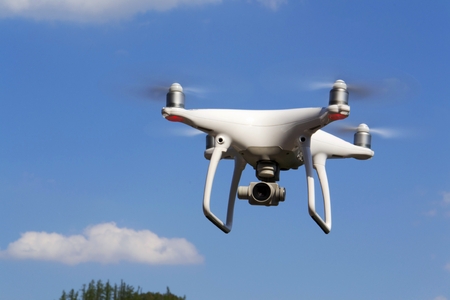 White drone quadrocopter with camera flying over forestの写真素材