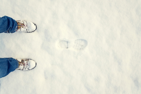 Winter shoes footprint in fresh snow, blue jeans trousers, copyspaceの写真素材