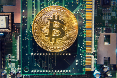 Golden bitcoin coin lying on computer motherboard, cryptocurrency mining conceptの写真素材