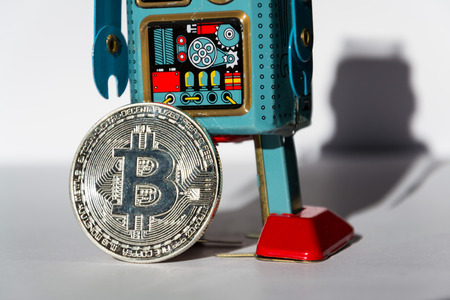Vintage tin toy robot with bitcoin coin, cryptocurrency mining concept