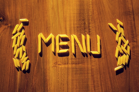 Menu letters from penne pasta on wooden table, cooking restaurantの写真素材