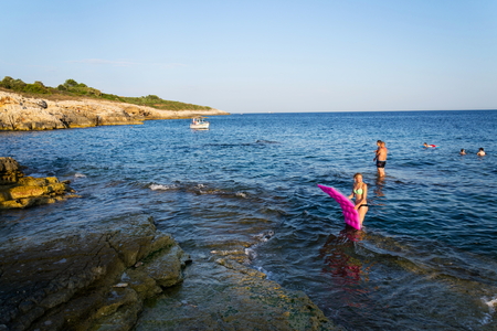 PREMANTURA, CROATIA - JULY 26: Boat with swimming people on Kamenjak peninsula by the Adriatic Sea on July 26, 2016 in Premantura, Croatia.のeditorial素材