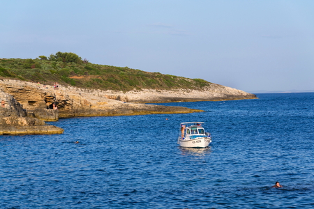 PREMANTURA, CROATIA - JULY 26: Boat with swimming people on Kamenjak peninsula by the Adriatic Sea on July 26, 2016 in Premantura, Croatia.のeditorial素材