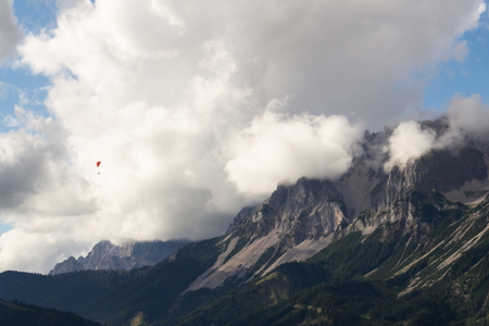 Paraglider flying over Schladming, Dachstein mountains background, Alps, Austriaの写真素材