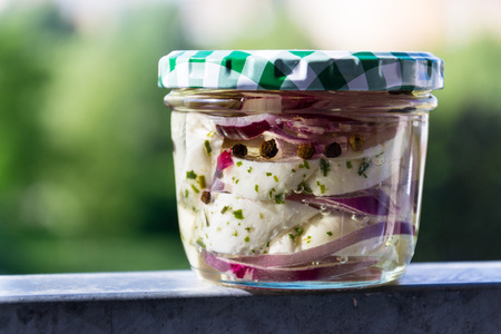 Marinated pickled cheese in oil with onions in glass jarの写真素材