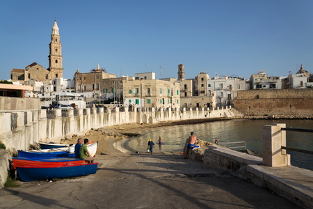 MONOPOLI, ITALY - JULY 2 2018: People swimming on beach Porta Vecchia near Cathedral during sunrise on July 2, 2018 in Monopoli, Italy.のeditorial素材