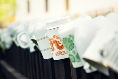 Beautiful cups laid upside down on wooden fence bars for wanderers refreshment, Asian dragon ornament, peace meditation wanderlust concept, Czech Republicの写真素材